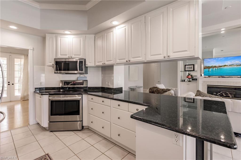 5163 Inagua Way Naples, FL 34119 - Photo 21 of 50 Kitchen featuring tasteful backsplash, stainless steel appliances, white cabinetry, dark stone counters, and light tile patterned flooring