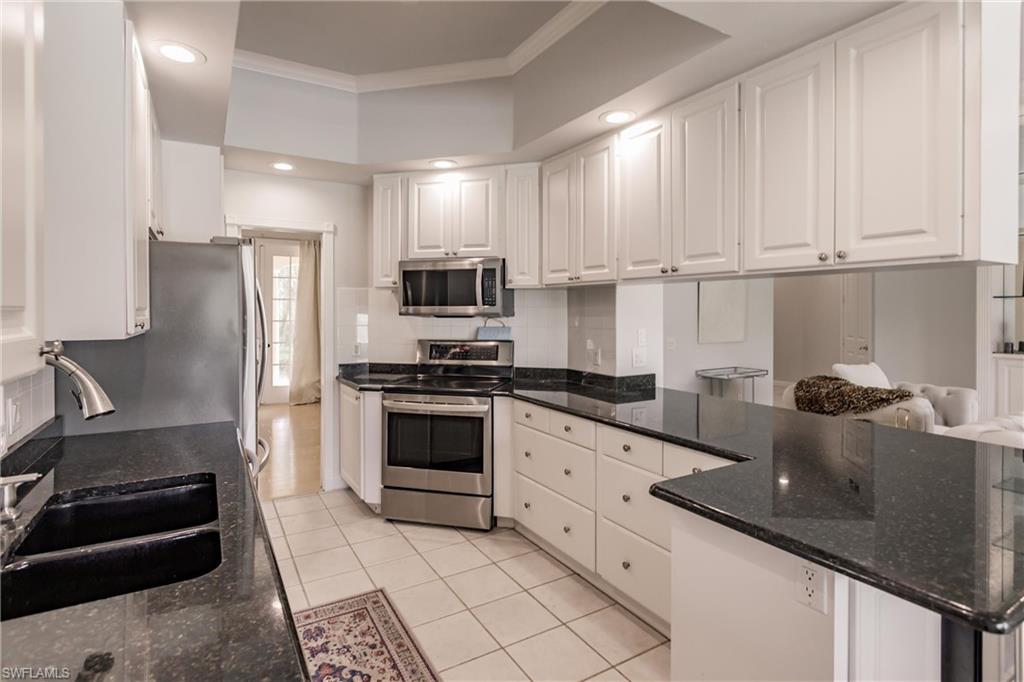 5163 Inagua Way Naples, FL 34119 - Photo 23 of 50 Kitchen with white cabinets, dark stone countertops, light tile patterned floors, crown molding, and appliances with stainless steel finishes