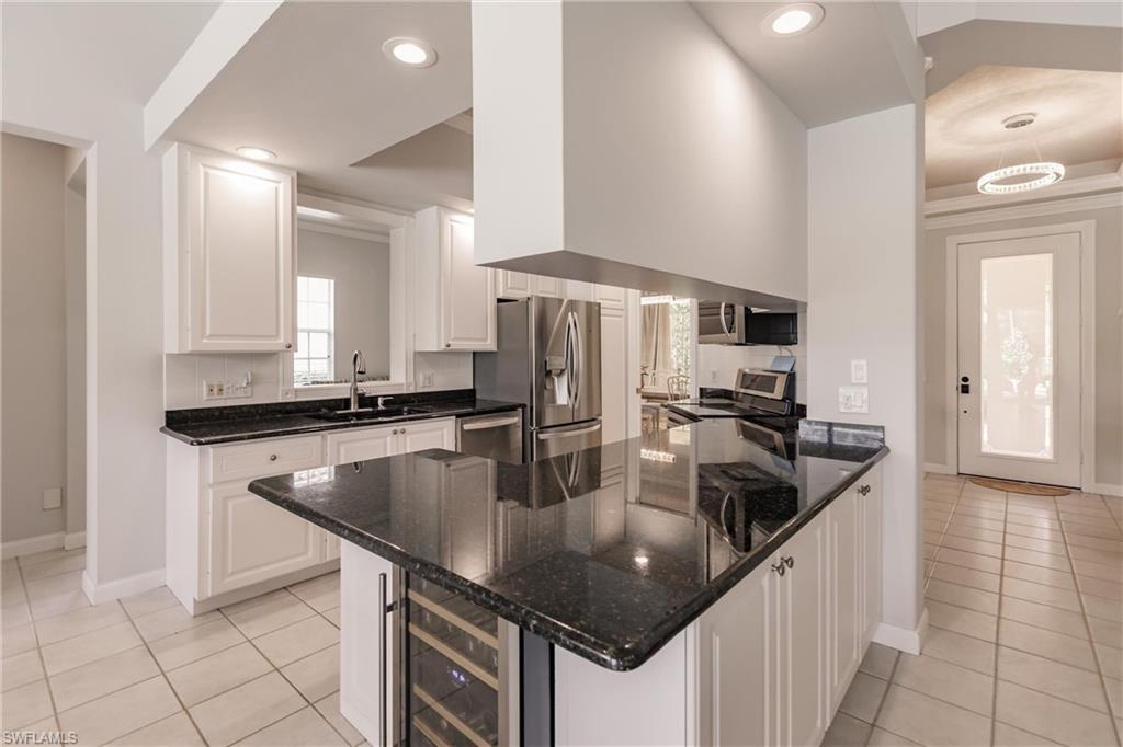 5163 Inagua Way Naples, FL 34119 - Photo 24 of 50 Kitchen featuring dark stone counters, appliances with stainless steel finishes, sink, and light tile patterned floors
