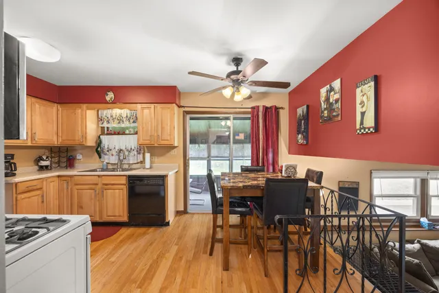 a kitchen with stainless steel appliances granite countertop a stove a refrigerator a dining table and chairs with wooden floor