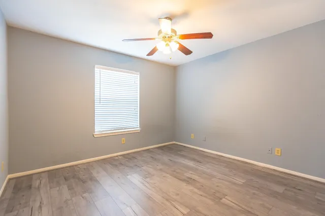 an empty room with a window and a fan