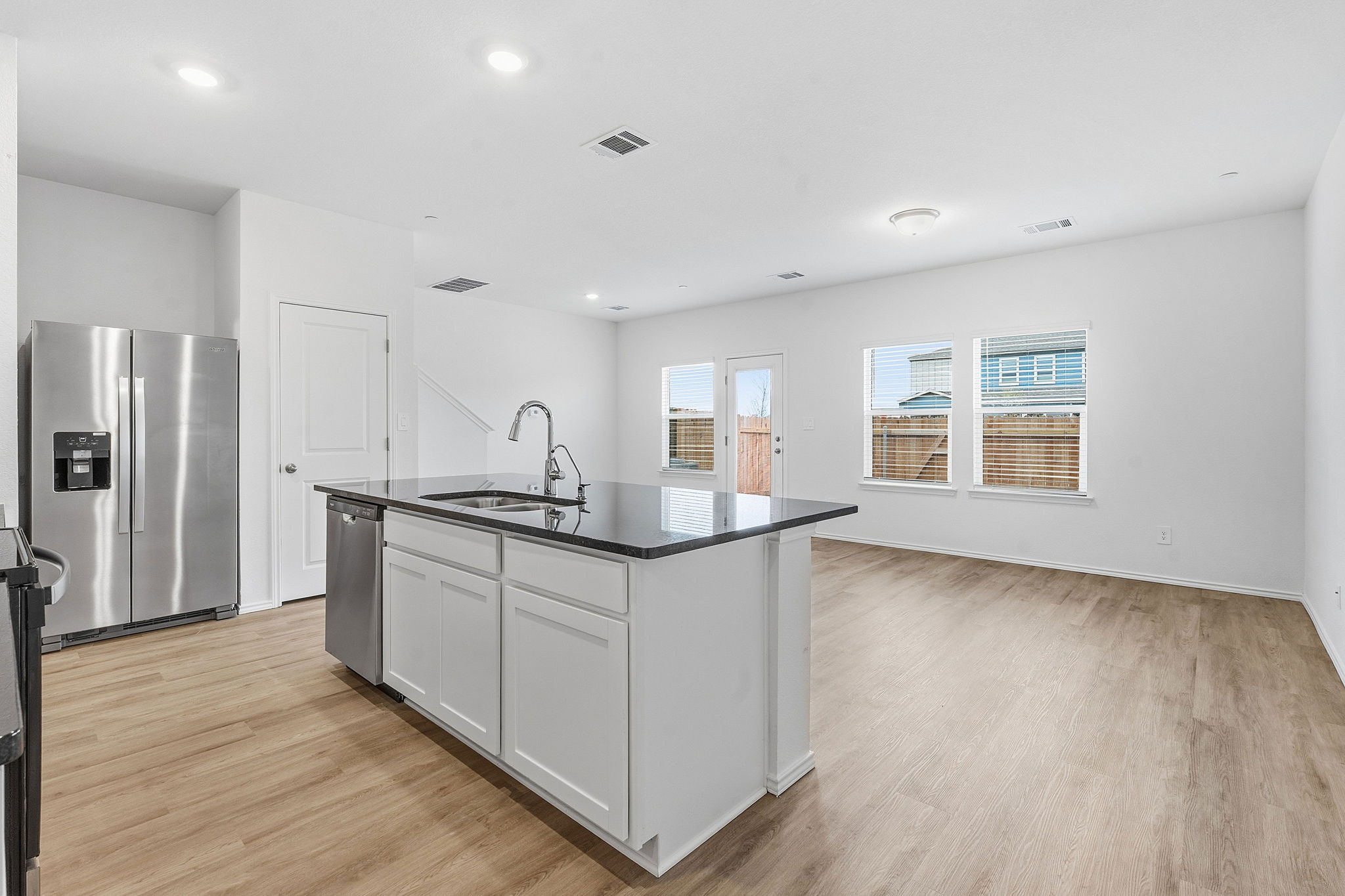 164 Cinnabar Lane, Unit 4 Kyle, TX 78640 - Photo 6 of 23 Open-concept living area featuring wood-finish flooring, a kitchen island with dark countertop and integrated sink, stainless steel appliances, and white cabinetry