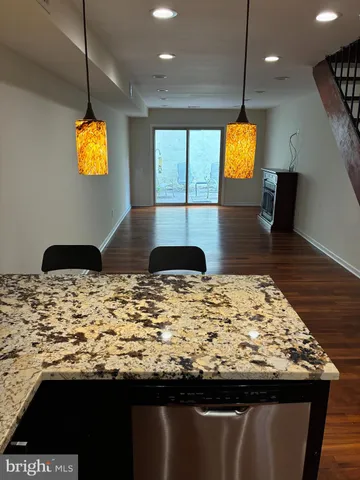 a room with kitchen island granite countertop wooden floor and a view of living room