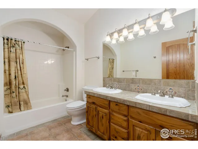 a bathroom with a granite countertop sink a toilet a mirror a bathtub and shower