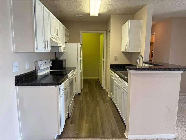a kitchen with granite countertop a sink a stove and cabinets