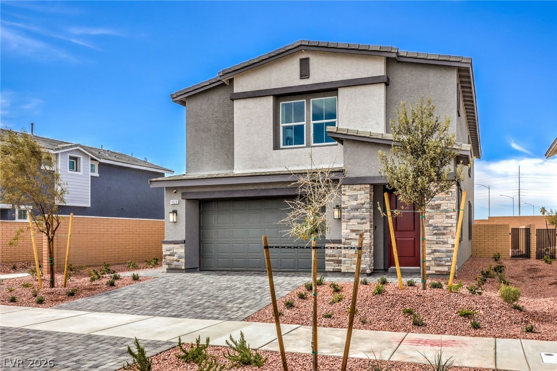 1017 Copper Robin Street Henderson, NV 89011 - Photo 2 of 43 Photo is representational only; actual home finishes may vary. View of front of home featuring stone siding, stucco siding, an attached garage, and decorative driveway
