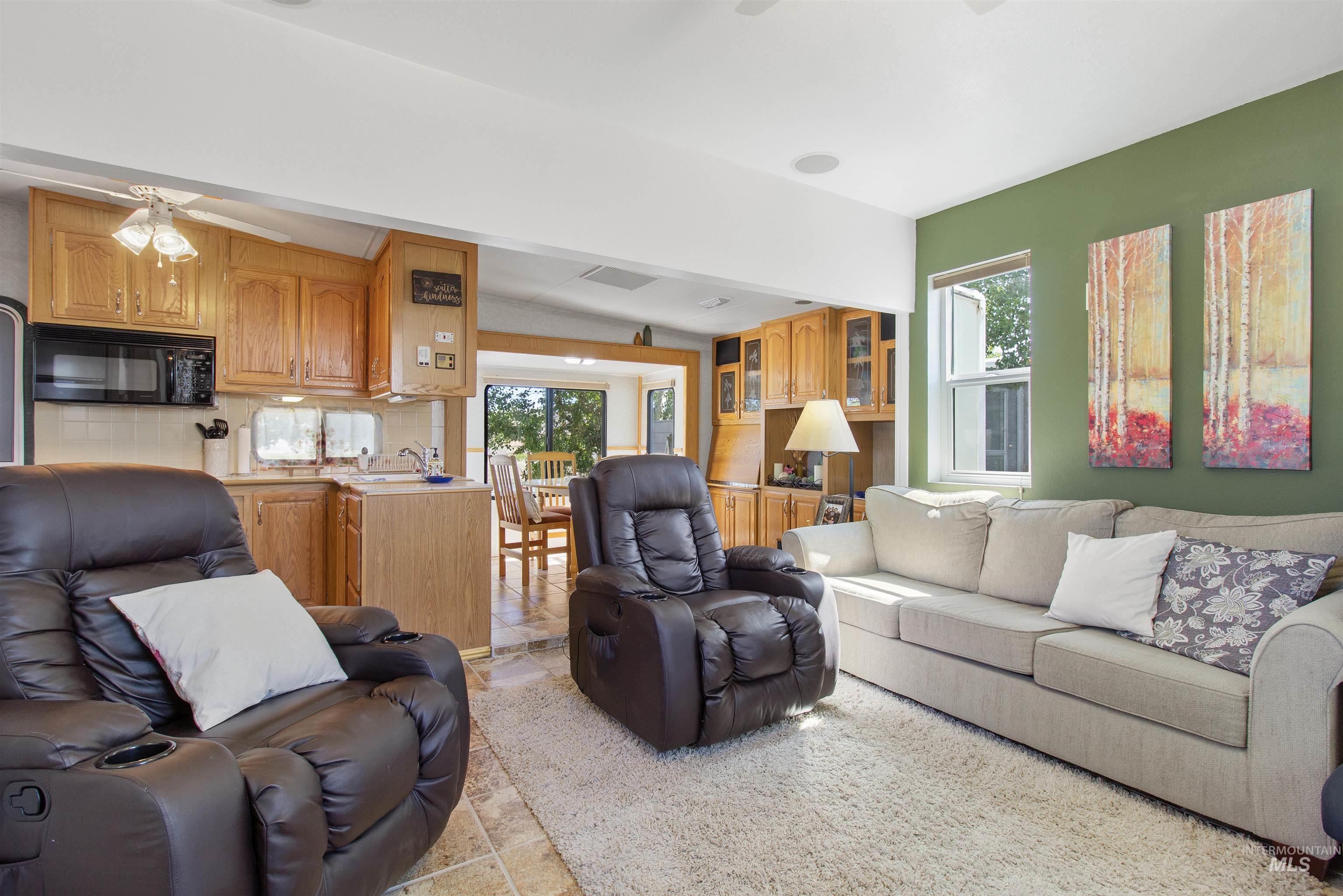 106 West Magic Road Shoshone, ID 83352 - Photo 5 of 45 Open-concept living space featuring wood-finish cabinetry, a built-in microwave, a tile backsplash, and a large window