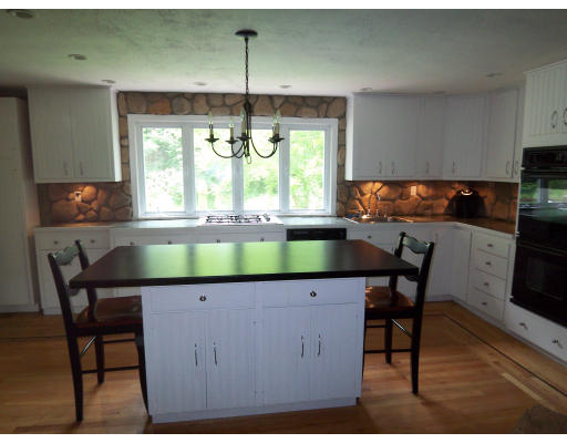 93 Concord Road Chelmsford, MA 01824 - Photo 2 of 18 a kitchen with a table chairs and a fireplace