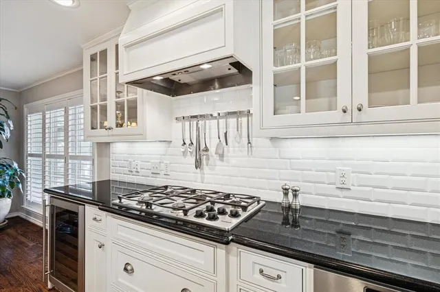 a kitchen with stainless steel appliances a stove top oven a sink a refrigerator white cabinets and wooden floor