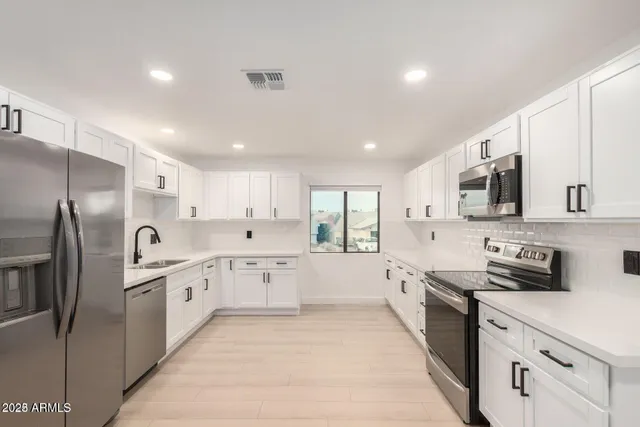 a large kitchen with stainless steel appliances lots of white cabinets