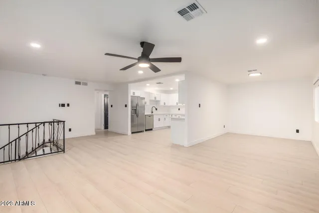 an empty room with a ceiling fan and windows