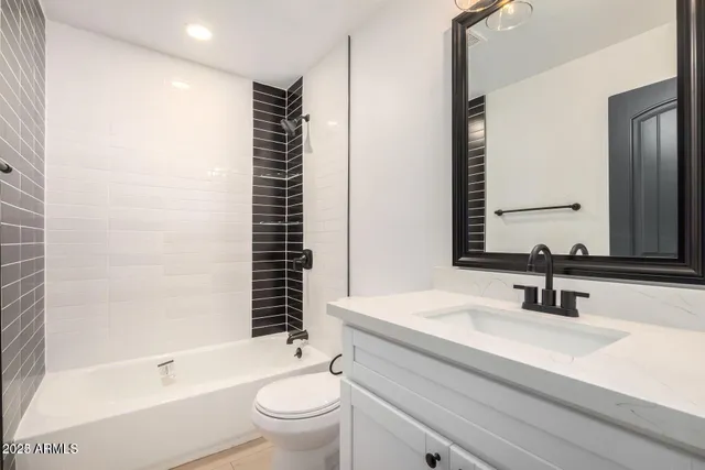 a bathroom with a bathtub shower sink vanity mirror and toilet