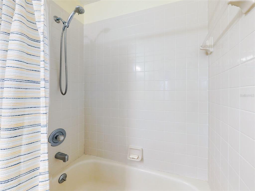 400 Bouchelle Drive, Unit 101 New Smyrna Beach, FL 32169 - Photo 21 of 63 a bathroom with a bath tub with a shower
