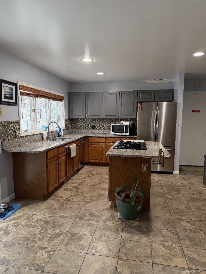 4 Greenlawn Road Cortlandt Manor, NY 10567 - Photo 2 of 24 Kitchen with a kitchen island, appliances with stainless steel finishes, tasteful backsplash, and light stone counters