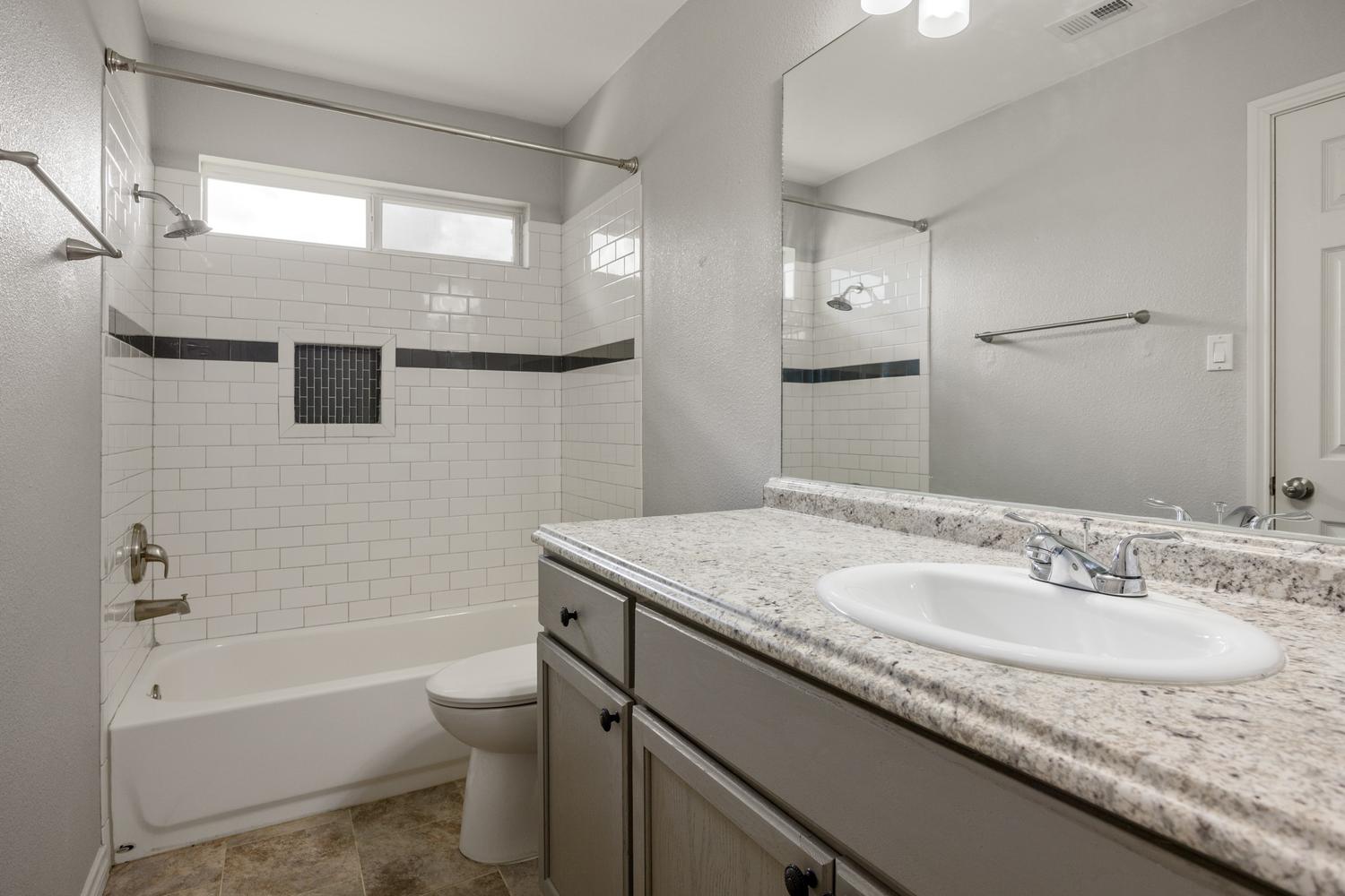 521 Britni Loop Kyle, TX 78640 - Photo 12 of 23 a bathroom with a granite countertop sink toilet and shower