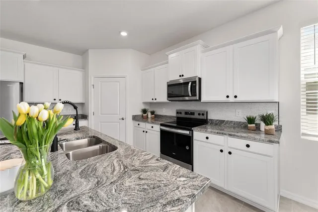 a kitchen with stainless steel appliances granite countertop a refrigerator a stove and a sink