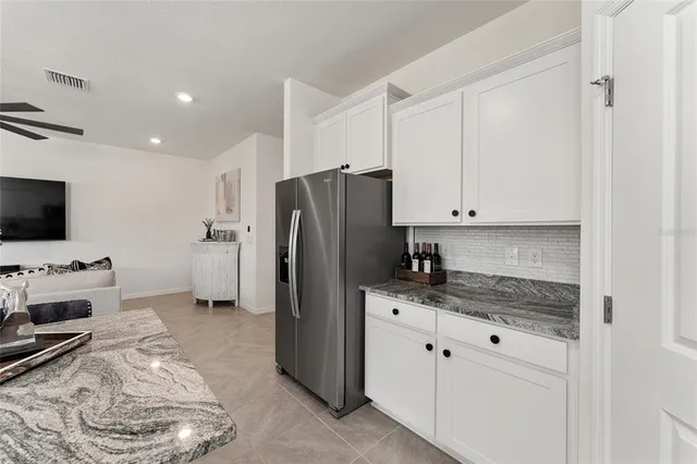 a kitchen with stainless steel appliances kitchen island granite countertop a table chairs sink and cabinets