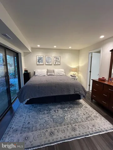 a bedroom with a bed a mirror on dresser and a rug