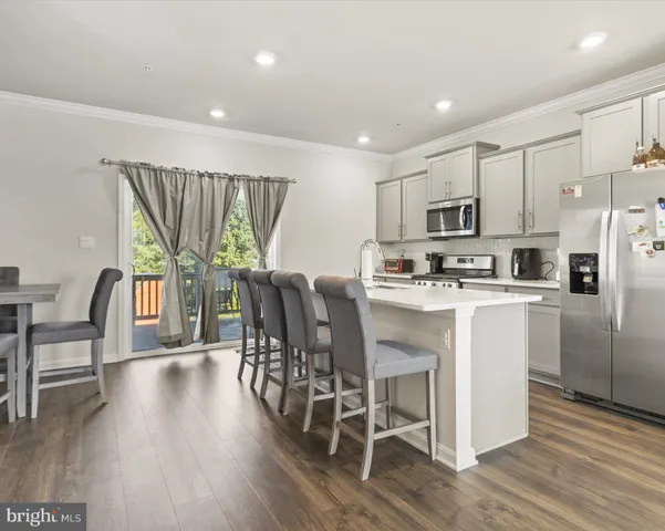 a kitchen with kitchen island wooden floors white cabinets and stainless steel appliances