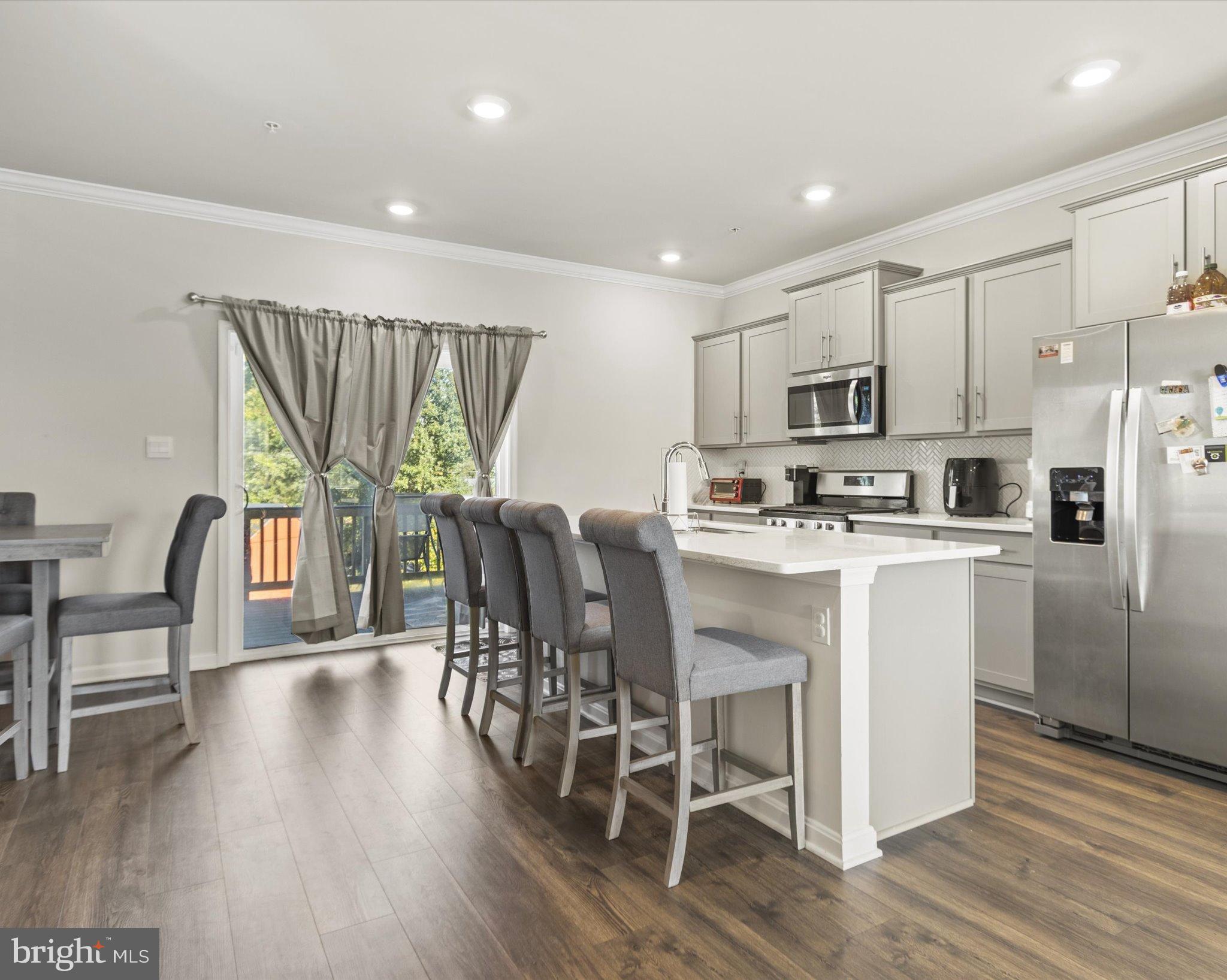 6610 Bullrush Court Clinton, MD 20735 - Photo 6 of 22 a kitchen with kitchen island wooden floors white cabinets and stainless steel appliances