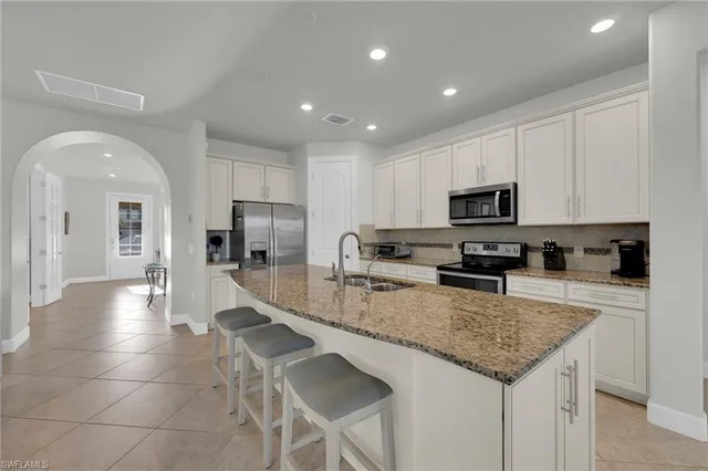 a kitchen with stainless steel appliances granite countertop a sink a stove a microwave a center island and cabinets