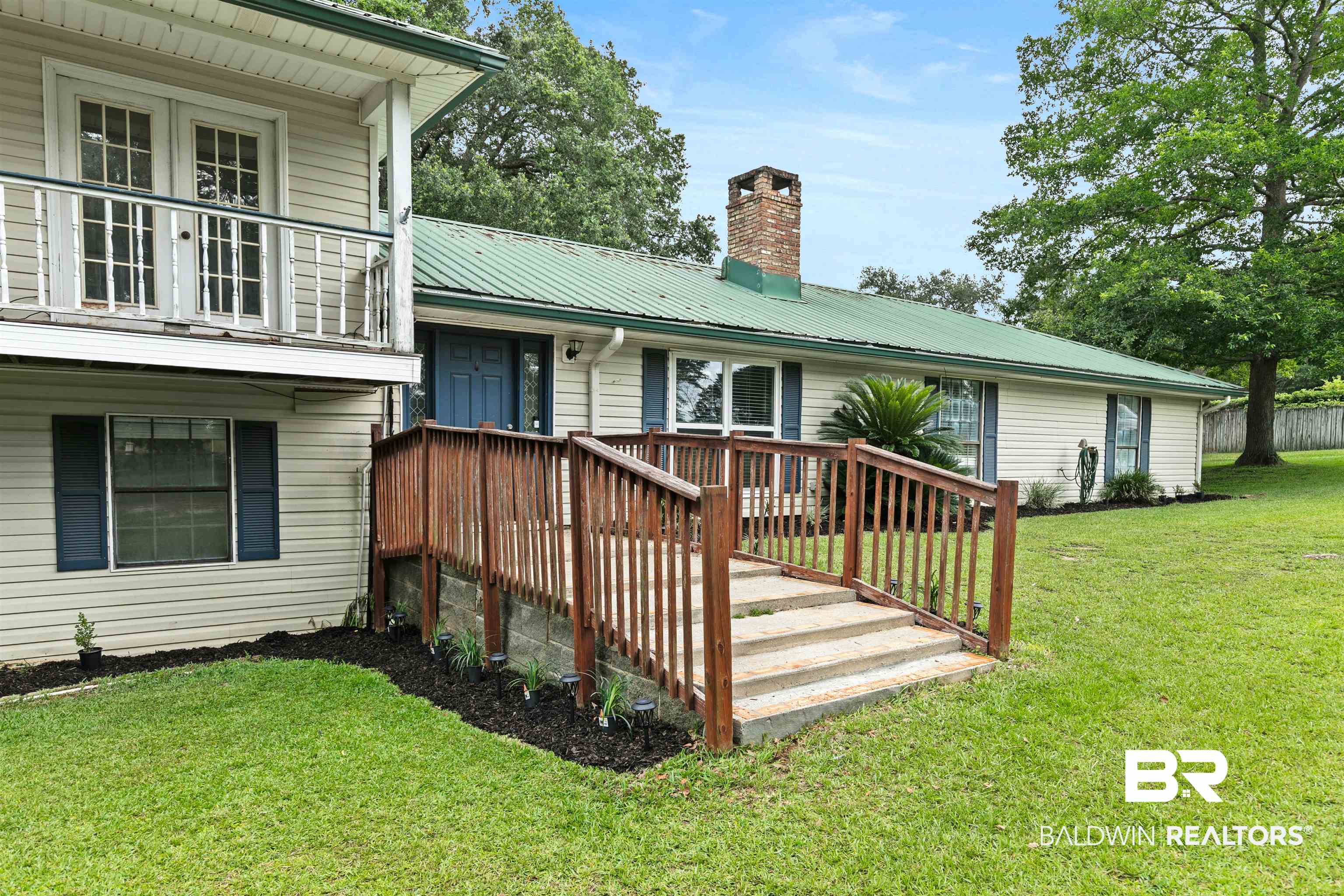 10420 Johnson Road South Mobile, AL 36695 - Photo 12 of 75 Exterior featuring light-colored siding, a green metal roof, and a prominent brick chimney