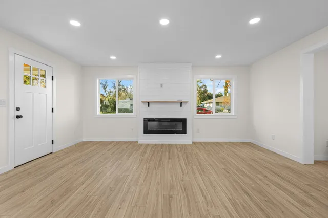 an empty room with windows and fireplace