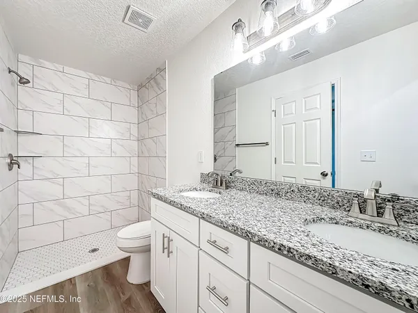 a bathroom with a granite countertop sink a toilet and shower