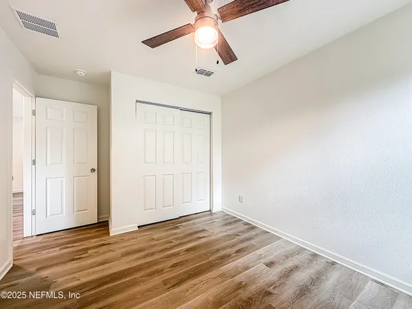 an empty room with wooden floor ceiling fan and windows
