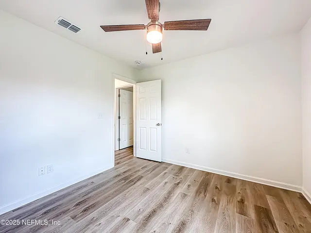 an empty room with wooden floor chandelier fan and closet in a room