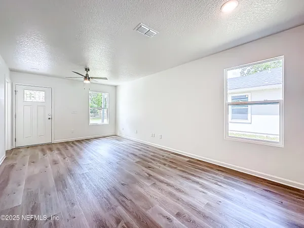 an empty room with wooden floor cabinet and windows