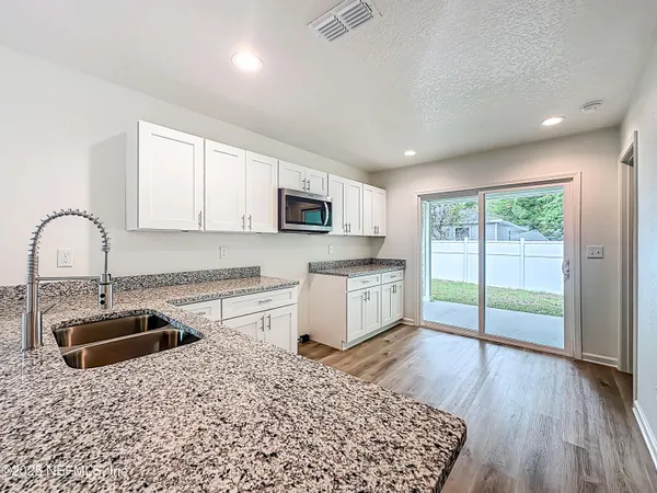 a kitchen with granite countertop a stove a sink and a microwave
