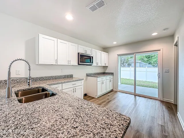 a kitchen with granite countertop a stove a sink and a microwave