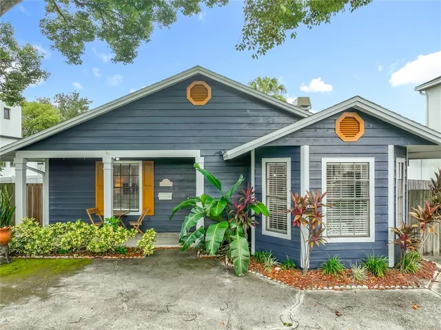 a view of a house with a small yard plants and a large tree