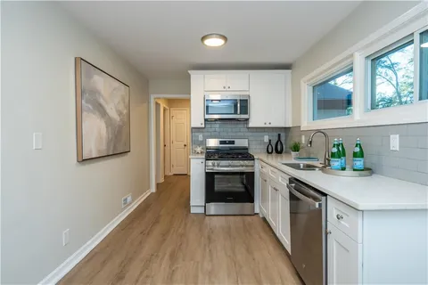 a kitchen with stainless steel appliances granite countertop a stove top oven a sink and dishwasher with wooden floor