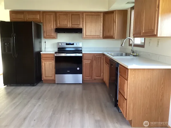 a kitchen with stainless steel appliances a sink a stove a refrigerator and cabinets