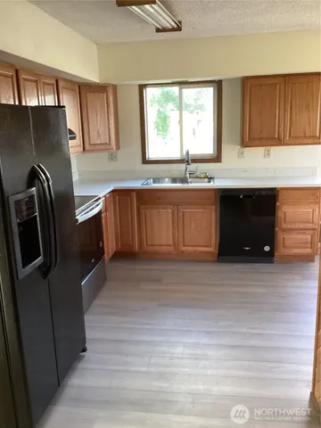 a kitchen with granite countertop a refrigerator and wooden cabinets