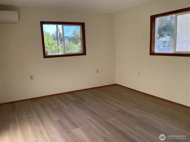 a view of an empty room with wooden floor and painting on the wall