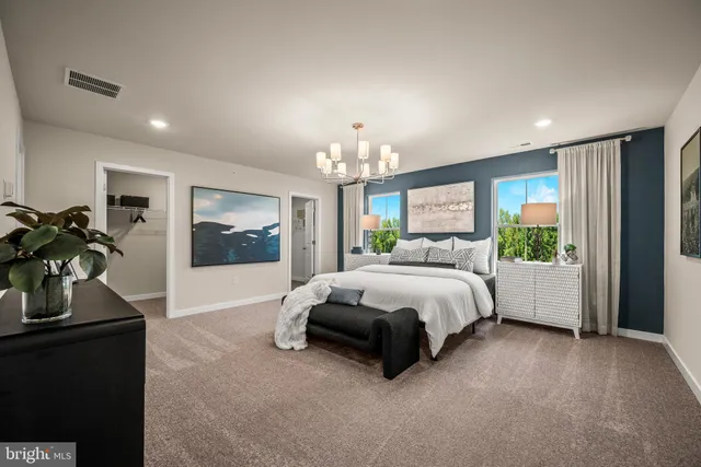 a spacious bedroom with a bed table flowerpot and window