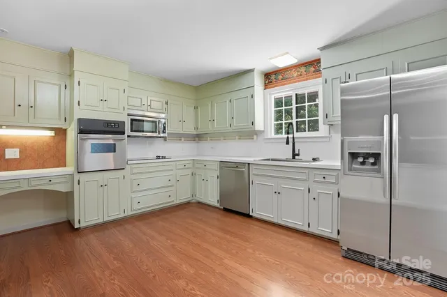 a kitchen with cabinets stainless steel appliances a sink and wooden floor
