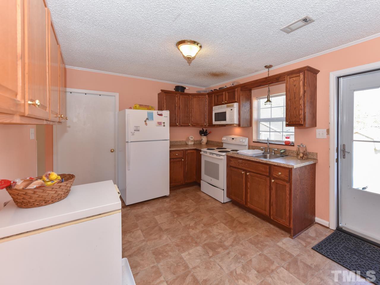 203 Smith Drive Garner, NC 27529 - Photo 3 of 13 a kitchen with granite countertop a refrigerator stove top oven and cabinets
