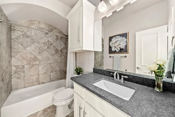 a bathroom with a granite countertop sink a toilet a mirror and shower
