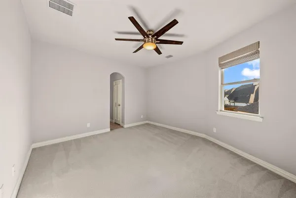 an empty room with ceiling fan and windows