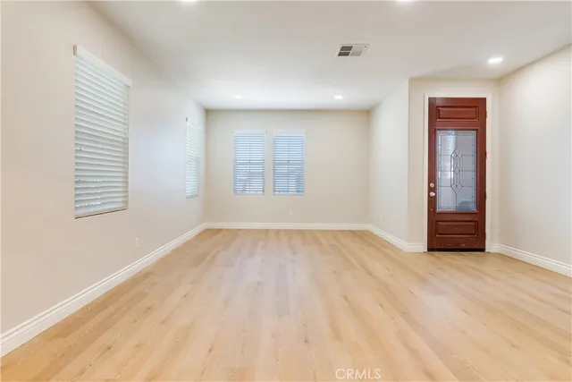 an empty room with wooden floor chandelier and windows