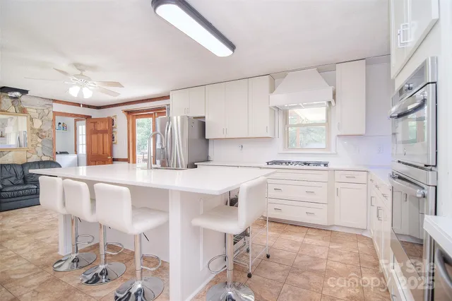 a kitchen with stainless steel appliances granite countertop a sink a stove and white cabinets with wooden floor