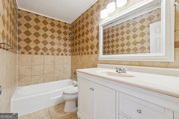 a bathroom with a granite countertop bathtub sink vanity mirror and toilet