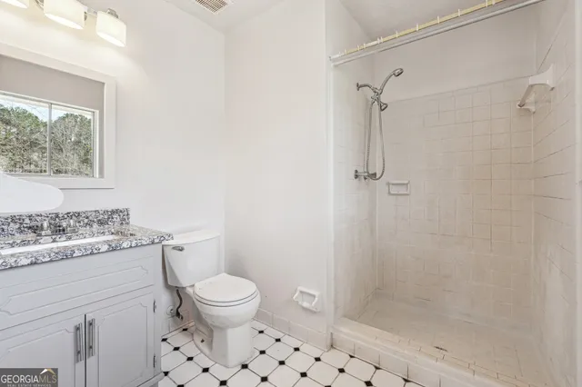 a bathroom with a granite countertop sink a toilet and shower
