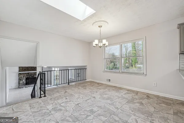 an empty room with chandelier fan and windows