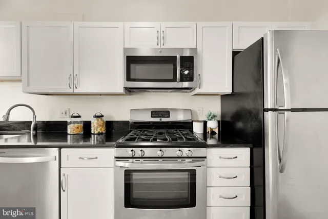 a kitchen with stainless steel appliances granite countertop white cabinets stove and microwave