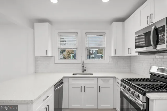 a kitchen with stainless steel appliances a sink stove top oven and white cabinets